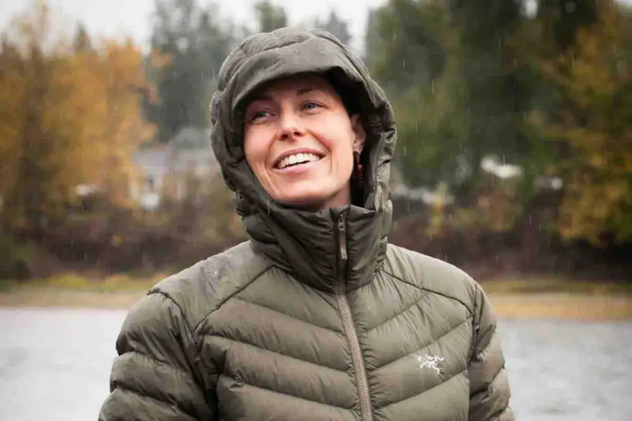 Mujer sonríe bajo la lluvia, con su chaqueta de Sorona Aura protegiéndola.