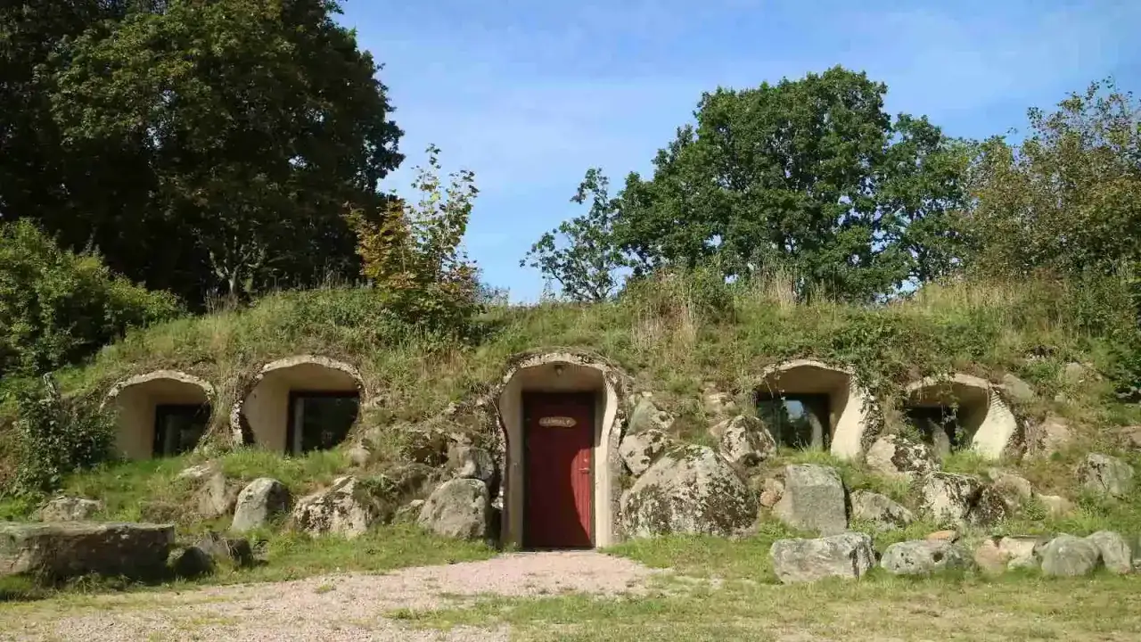 Unikt vandrarhem i Sk&aring;ne, inb&auml;ddat i en gr&ouml;nskande kulle med runda f&ouml;nster och en r&ouml;d d&ouml;rr.