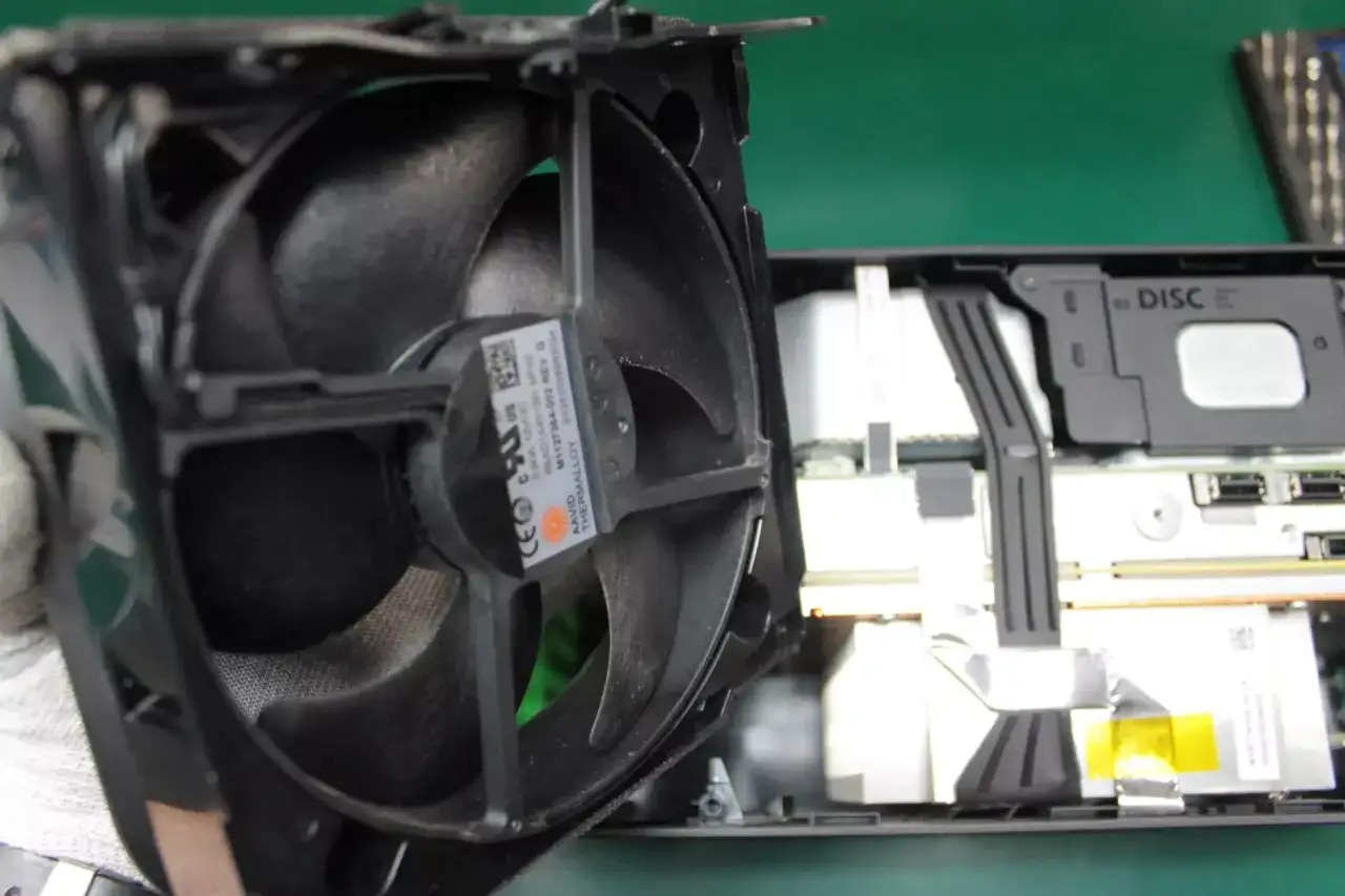 Wiatrak konsoli Xbox Series X podczas czyszczenia. Widać wnętrze konsoli i dysk.