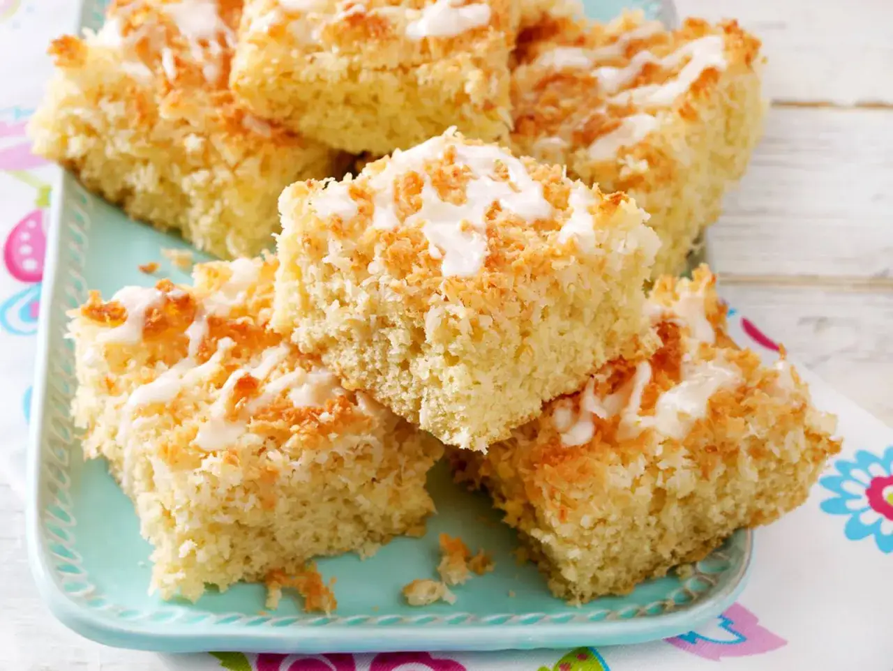 Saftiger Kuchen mit Kokosmilch, bestreut mit gerösteter Kokosnuss und einem Zuckerguss.