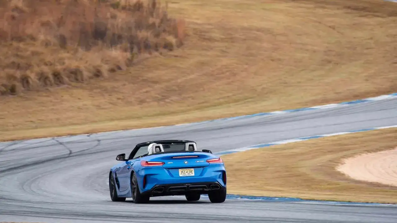 Niebieskie z4 bmw na torze wyścigowym, z widokiem na suche, trawiaste zbocza.