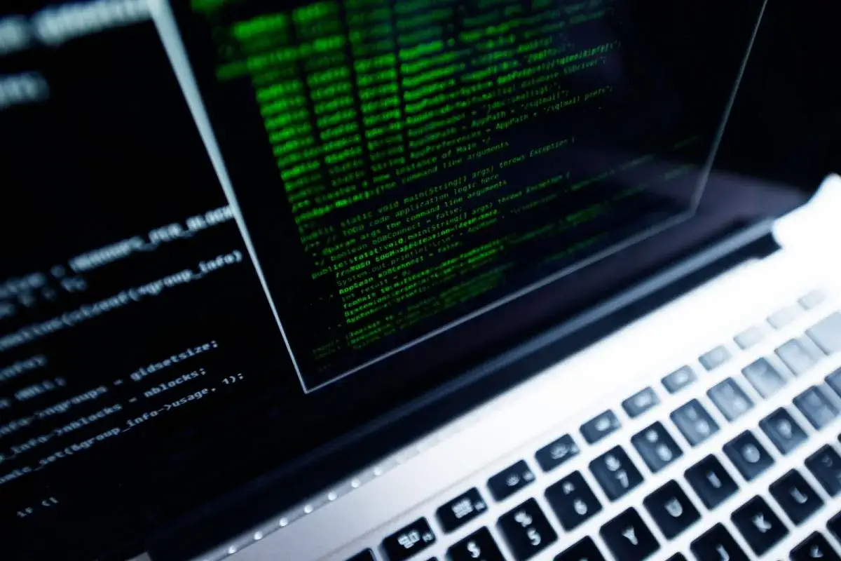 Zielony kod na ekranie laptopa, symbolizujący pracę programisty.
