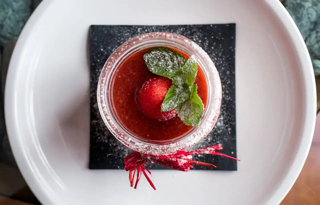 Delizioso bavarese alle fragole in un bicchiere, guarnito con una fragola intera, menta e zucchero a velo.