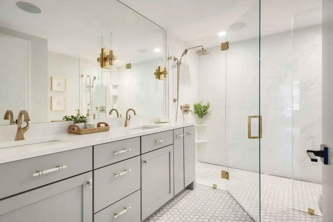 Elegant modern double vanity bathroom ideas feature a grey vanity, brass fixtures, and a marble shower.