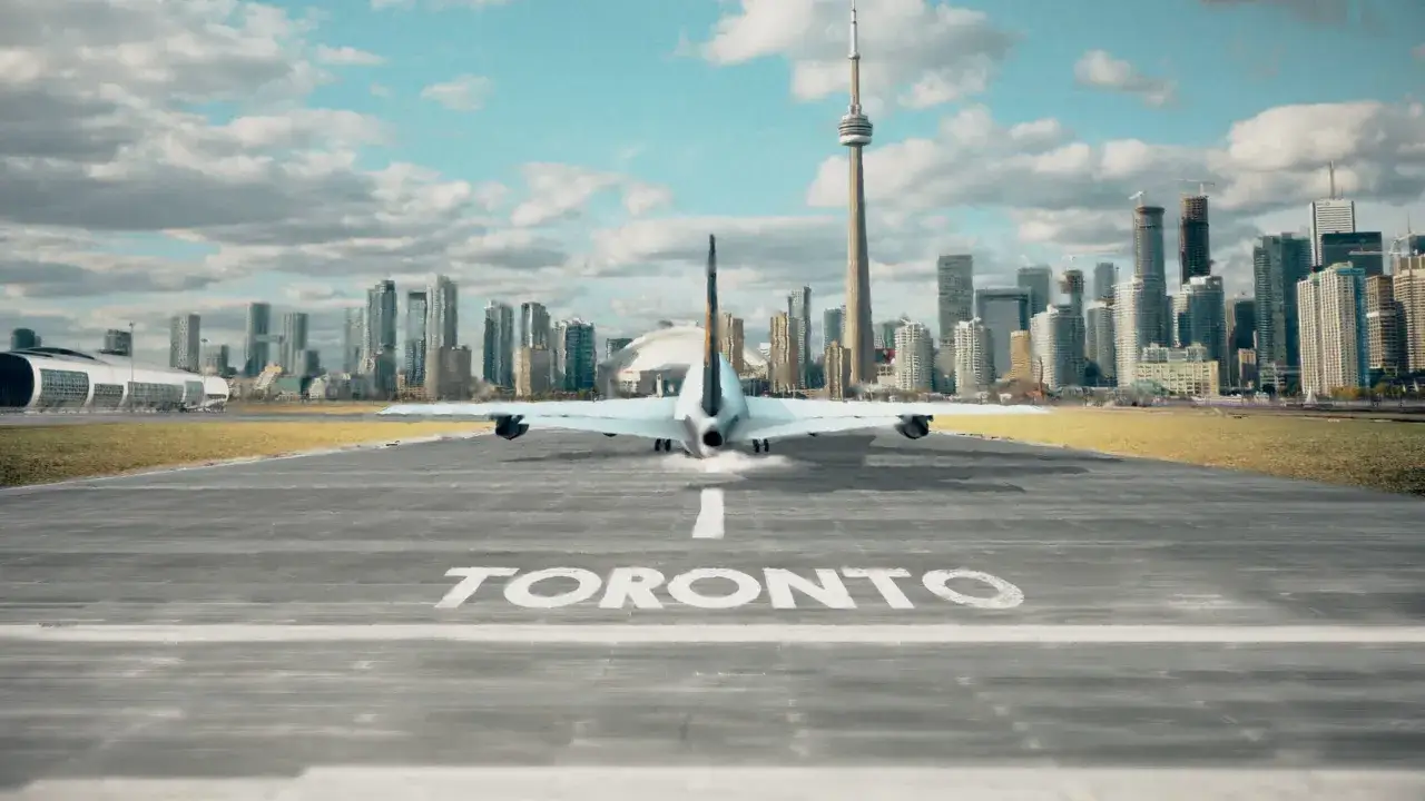 Samolot ląduje na pasie startowym z napisem TORONTO. W tle widać panoramę miasta i wieżę CN.