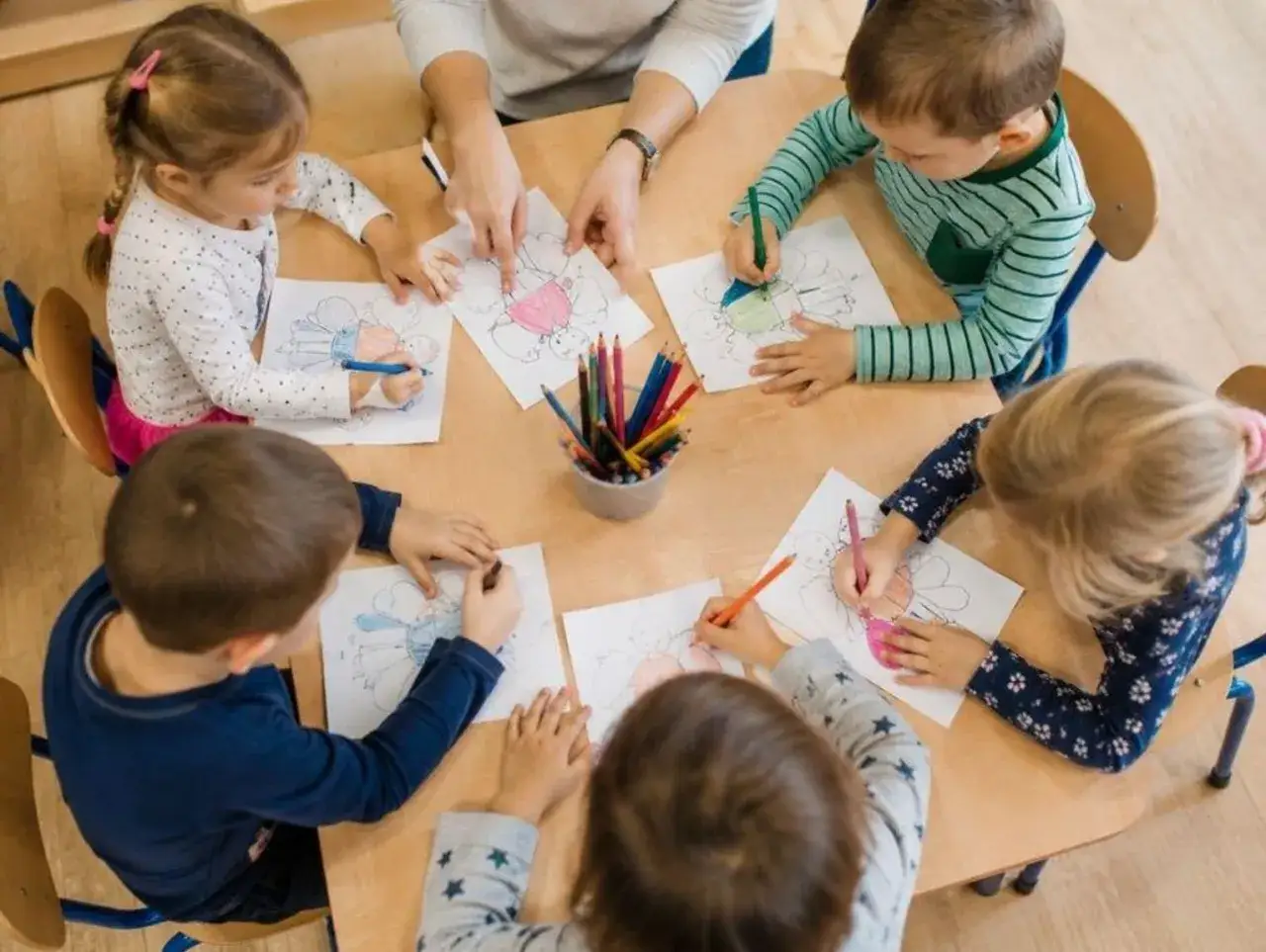 Dzieci rysują kredkami przy stole. Zastanawiasz się, jak przenieść dziecko do innego przedszkola?
