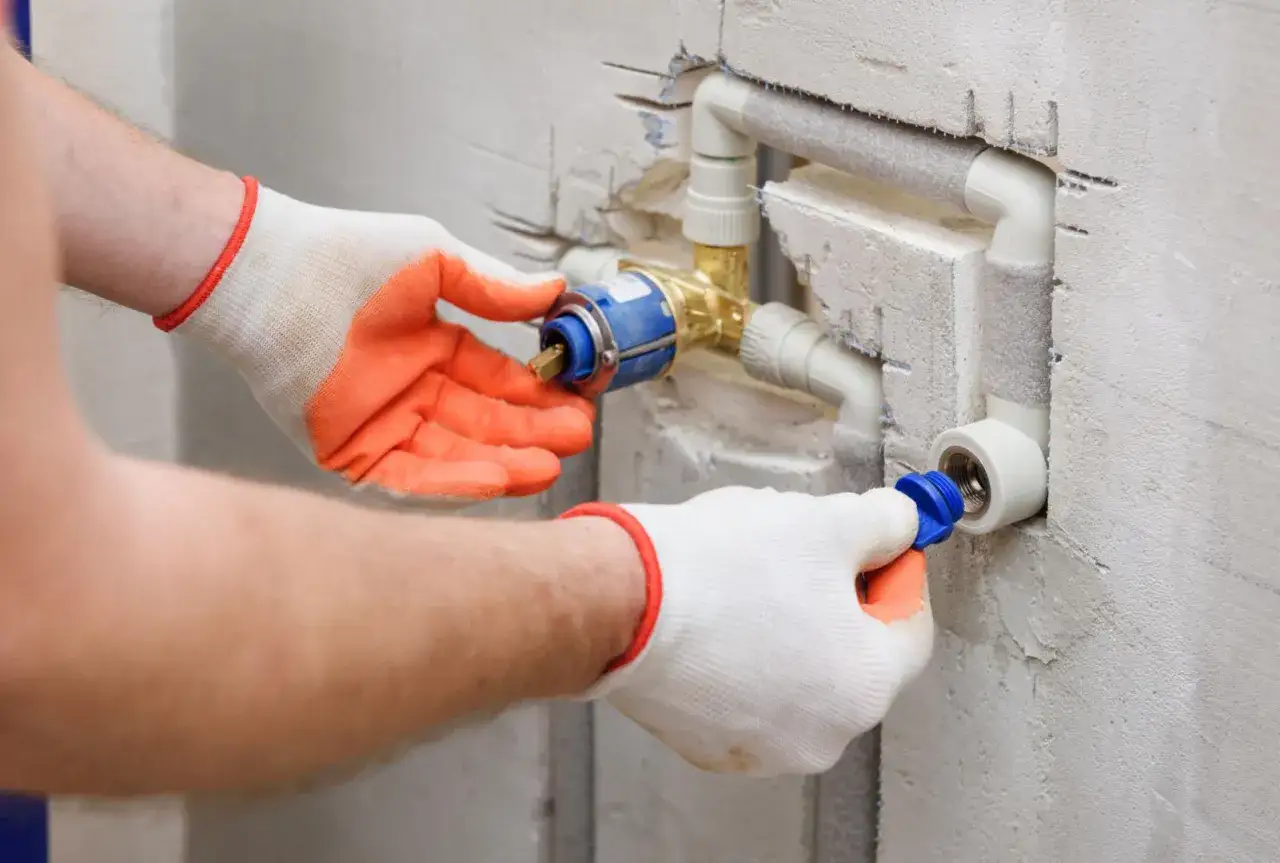 Instalator w rękawiczkach montuje zaw&oacute;r, kt&oacute;ry pomoże jak zwiększyć ciśnienie wody w instalacji.