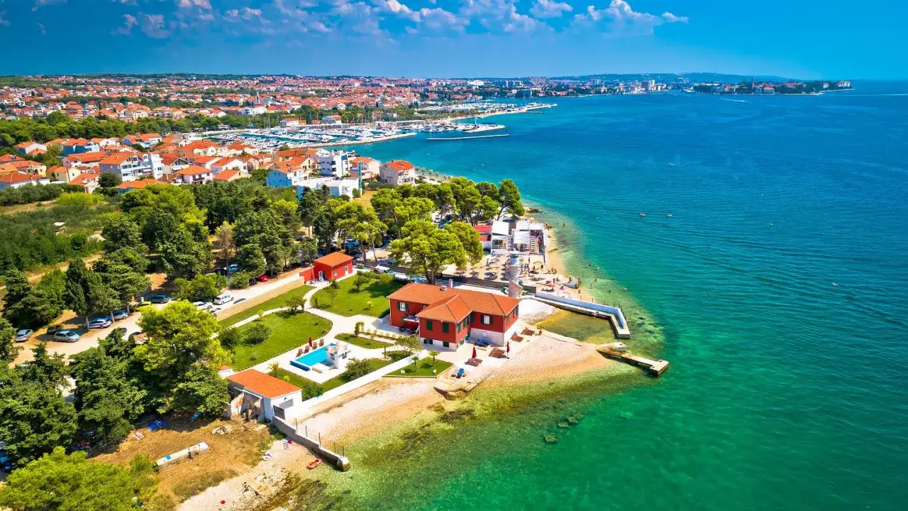 Piękna pogoda w Zadarze we wrześniu. Widok na wybrzeże z willami, plażą i turkusowym morzem.