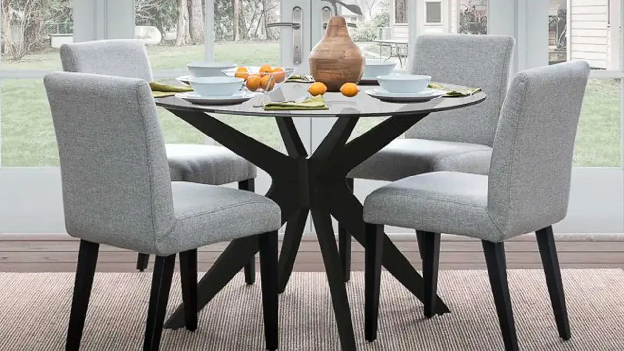 Ideas para como decorar una mesa redonda: centro de mesa con jarrón y naranjas, vajilla clara y servilletas verdes.