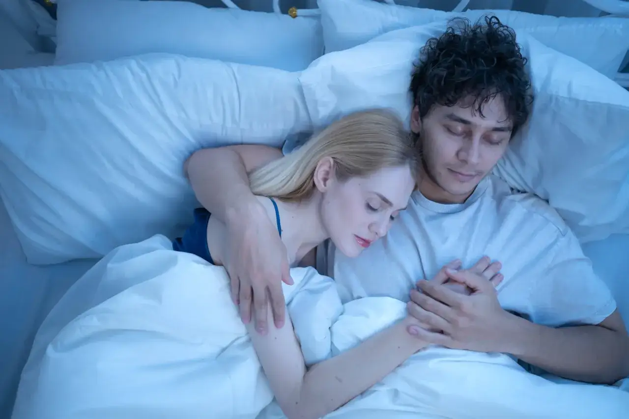 Ein Paar schl&auml;ft friedlich in einem Bett, Arm in Arm. Sie genie&szlig;en die Ruhe und Geborgenheit, wenn sie zusammen einschlafen.