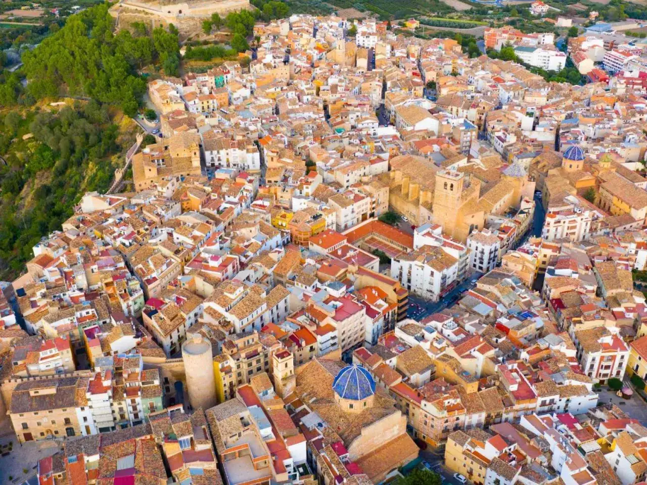 Vista aérea de un pueblo con tejados naranjas y casas blancas, con una iglesia de cúpula azul. Un ejemplo de los pueblos bonitos cerca de Benicassim.