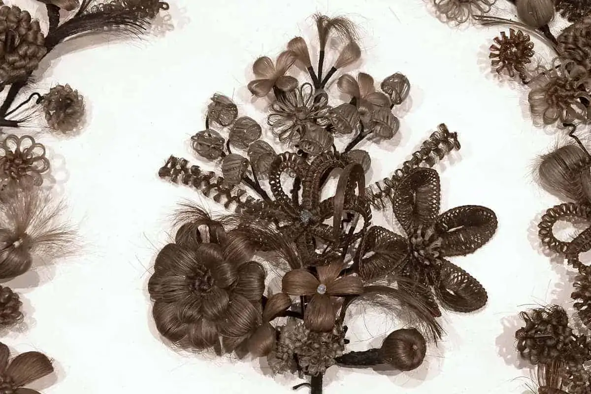 Intricate hair art forms a bouquet of flowers and decorative elements, showcasing the delicate craft of hair weaving.