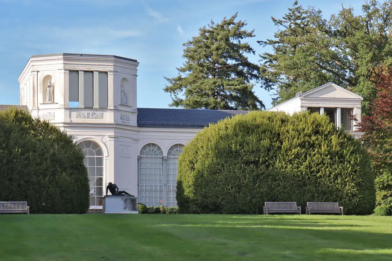 Das Schloss Putbus, ein klassizistisches Gebäude, umgeben von üppigem Grün und einem Denkmal.
