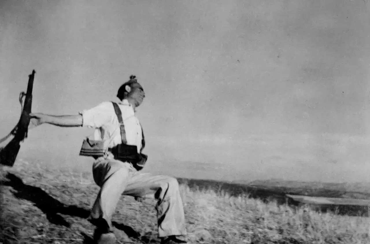 Soldat en mouvement, fusil à la main, sur une colline. Une photo historique choquante qui capture un instant de conflit.