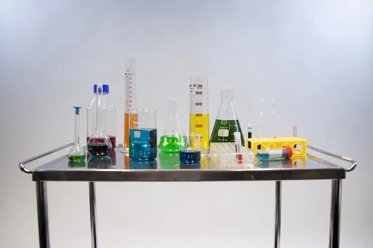 Kolorowe płyny w kolbach i probówkach na wózku laboratoryjnym. To inspiracja, jak otworzyć laboratorium chemiczne.