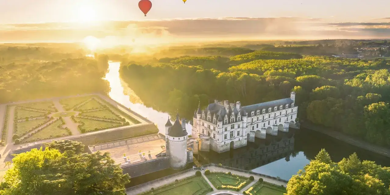 Le château de Chenonceau, un joyau des châteaux de la Loire à visiter absolument, se reflète dans l'eau au lever du soleil.
