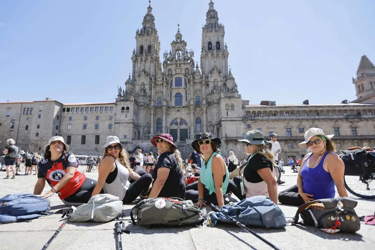Peregrinas descansan frente a la Catedral de Santiago. Ellas han completado el Camino de Santiago, una ruta de peregrinación milenaria que se hace por motivos espirituales, culturales o personales.