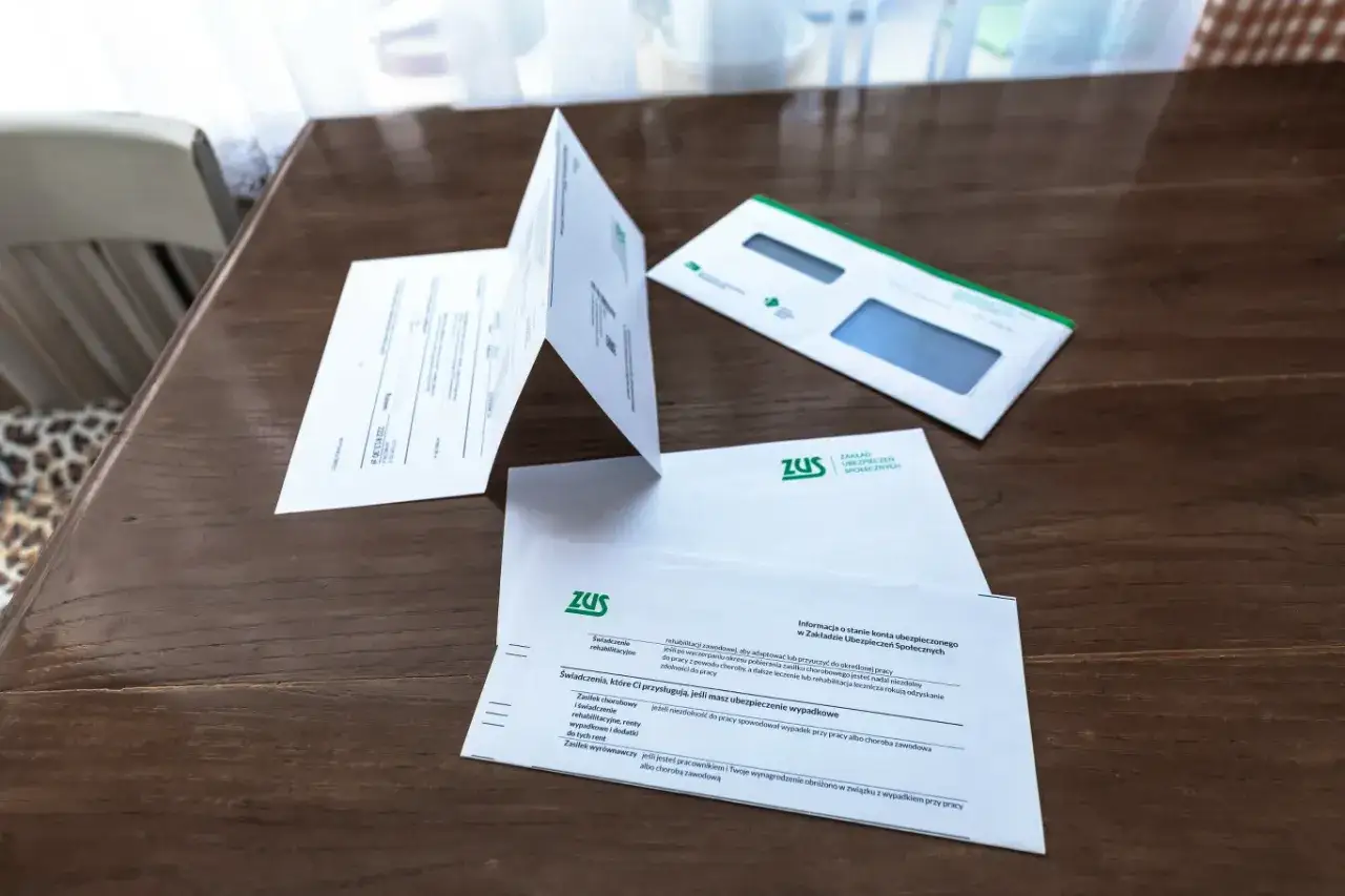 Dokumenty ZUS na drewnianym stole. Informacje o świadczeniach, które mogą stanowić ulgę dla pracujących seniorów.