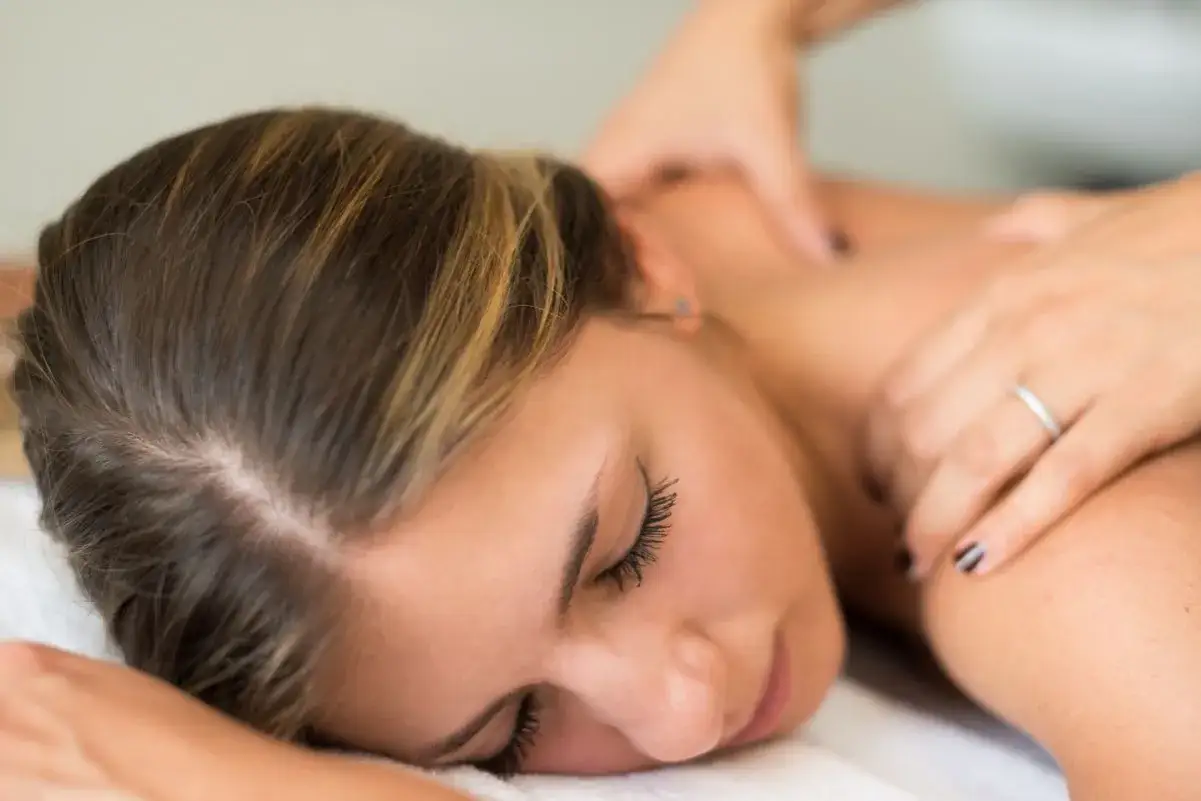 Relaksacyjny masaż na spięte mięśnie karku i ramion. Delikatne dłonie terapeuty przynoszą ulgę.