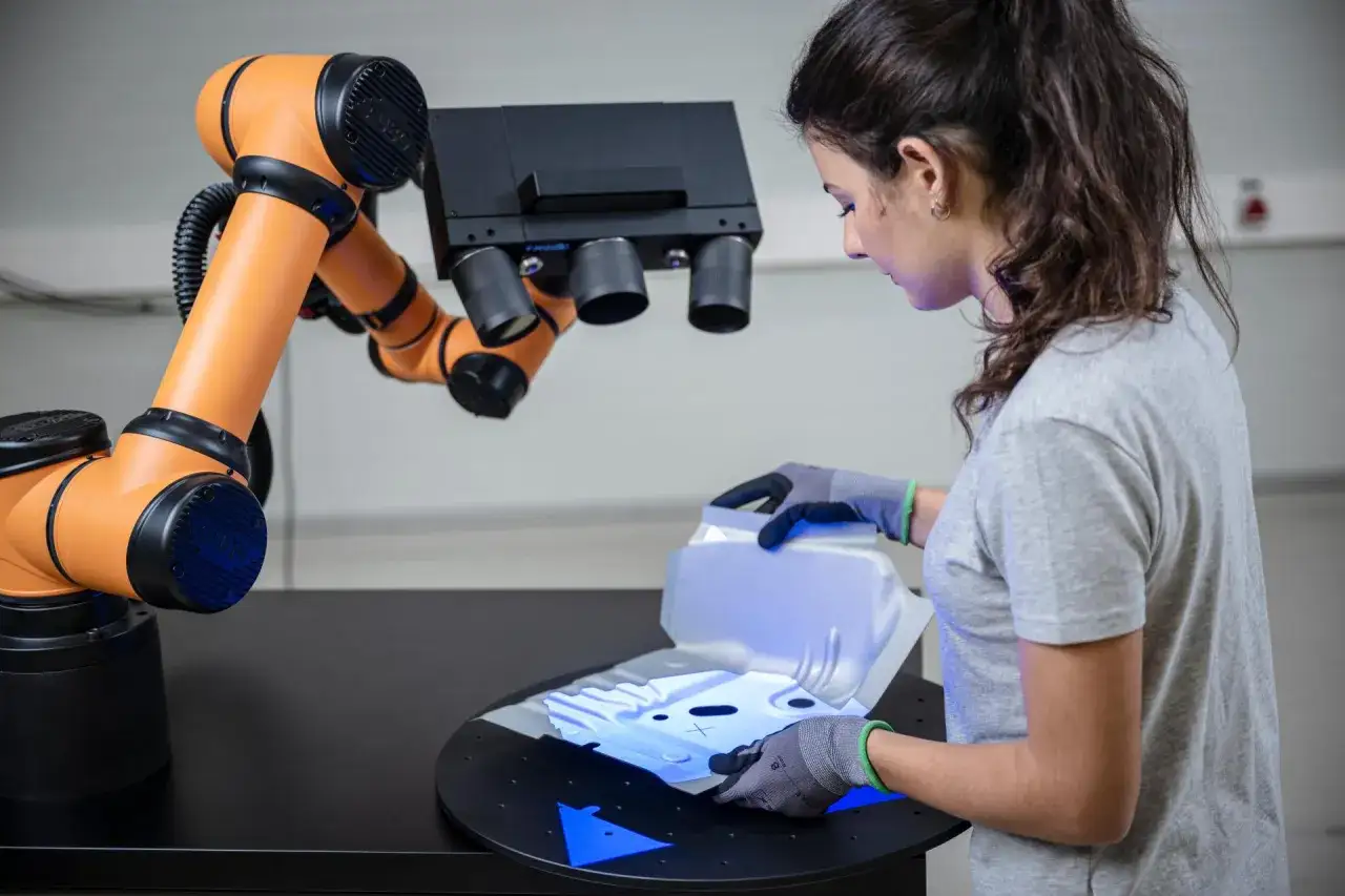 Kobieta w rękawiczkach umieszcza element do skanowania 3D. Robot i skaner wykonają precyzyjny mikrometr pomiar.