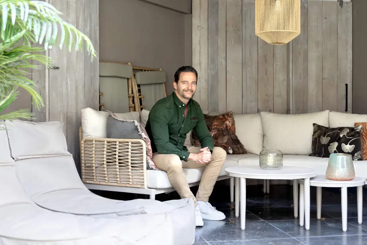Merijn van de Laar ontspant op een comfortabele loungebank, omringd door sfeervolle kussens en een bamboe accent.