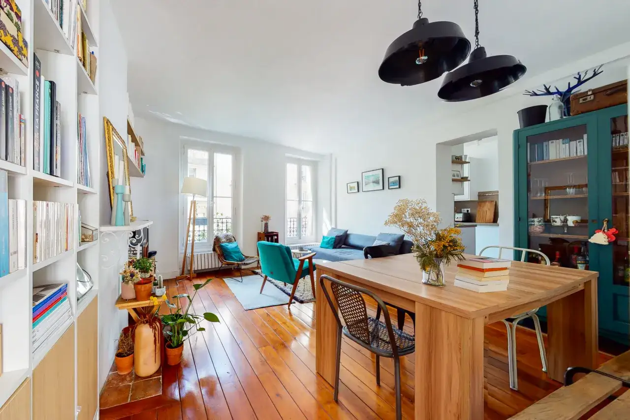 Salon lumineux avec parquet, meubles design et étagères remplies. Idéal pour vendre un appartement loué, prêt à accueillir de nouveaux locataires.
