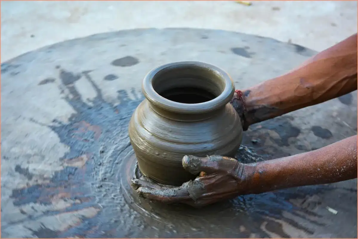 Manos de alfarero dan forma a una vasija en una rueda giratoria, un eco del **inventor de la rueda** y su ingenio.
