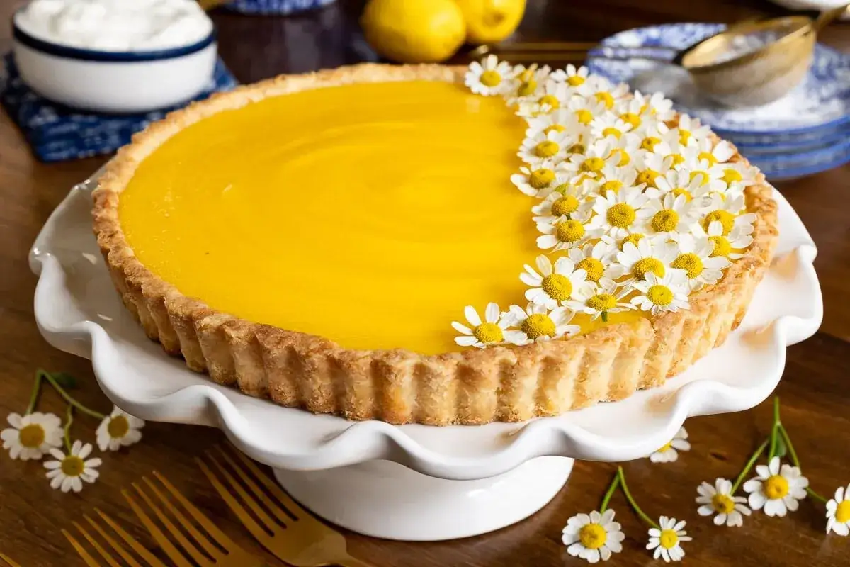 Tarte au citron éclatante, sa crème patissiere citron est décorée de marguerites fraîches. Un délice printanier.