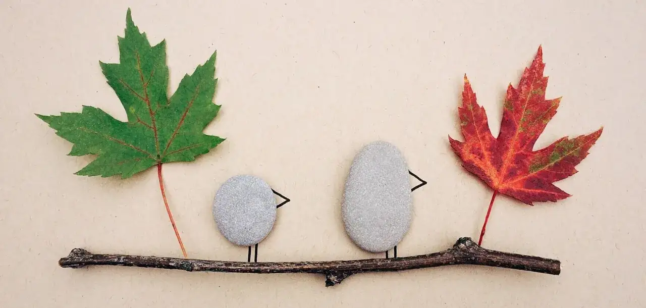 Dos pajaritos hechos de piedras y hojas de otoño, perfectos para manualidades preescolar.