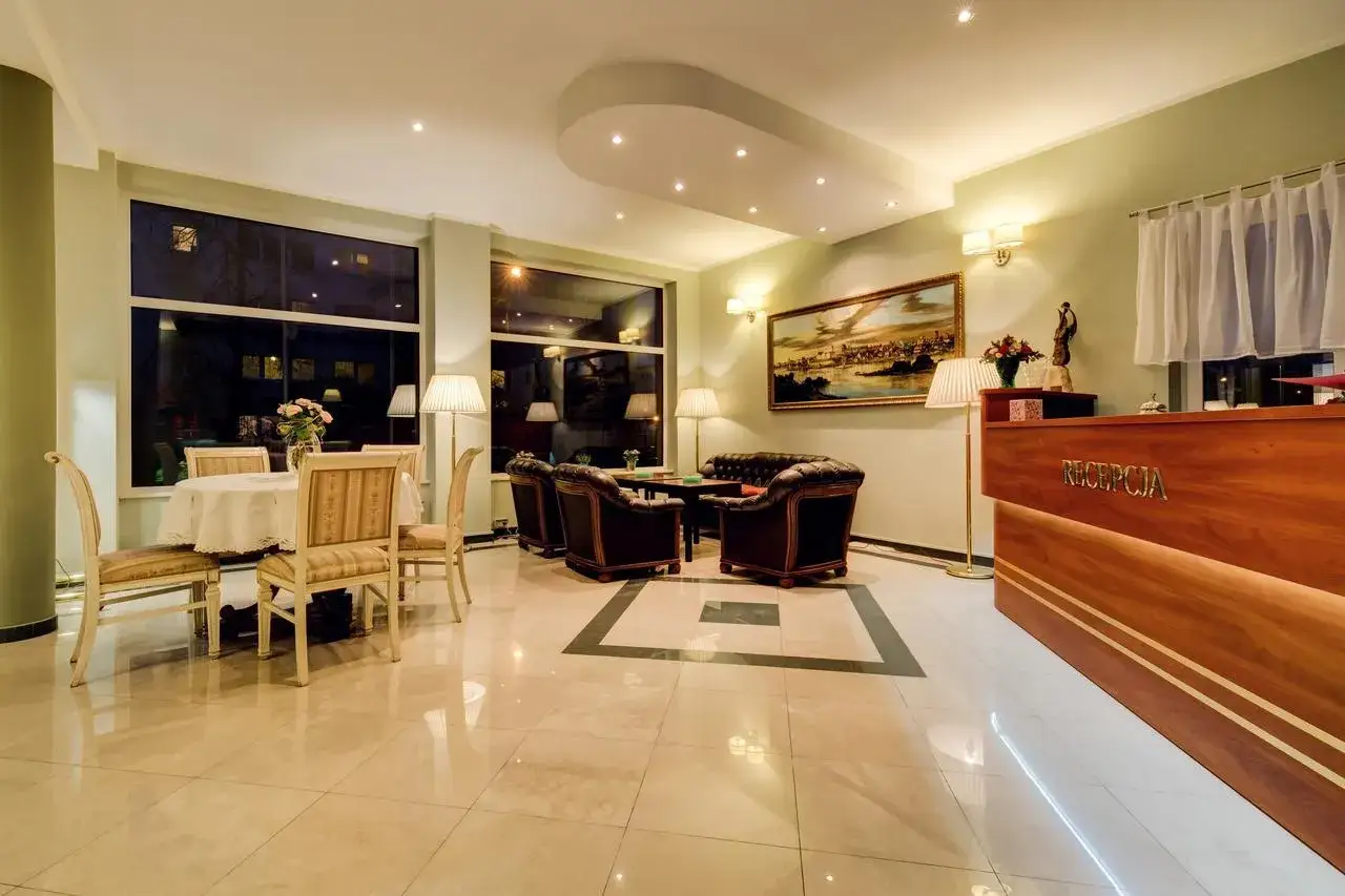 Eleganckie wnętrze recepcji Villa Plaza Warszawa z wygodnymi fotelami, stolikiem i obrazem na ścianie.