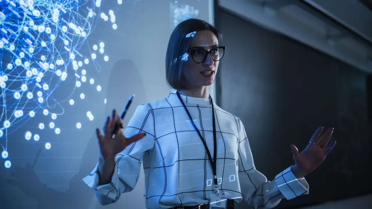 Donna con occhiali presenta un grafico di rete neurale, con la sua laurea per insegnare alle superiori.