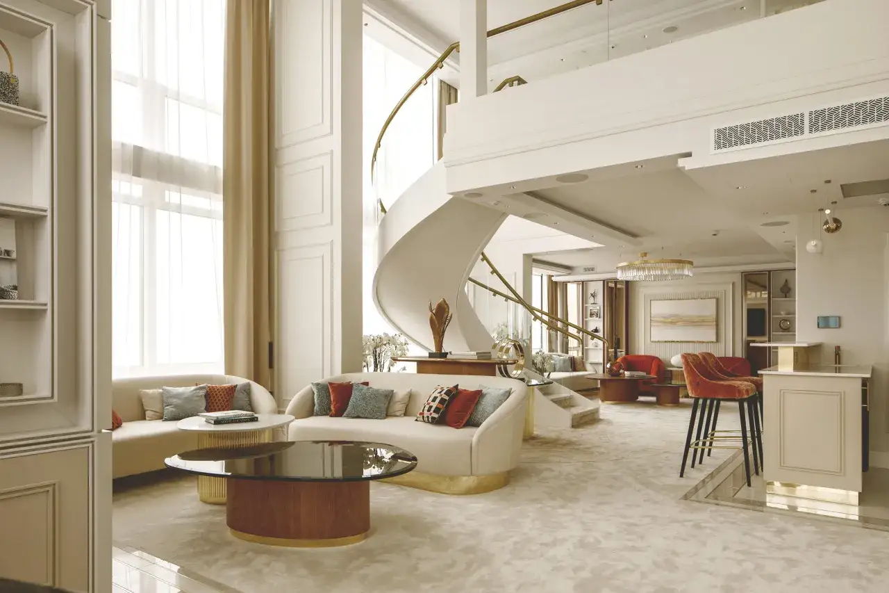 Eleganckie wnętrze apartamentu w sieci luksusowych hoteli. Spiralne schody, wygodne sofy i stylowy bar tworzą atmosferę wyrafinowania.