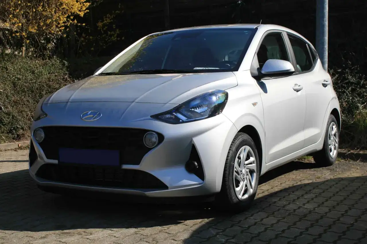 Silberner Hyundai i10, der auf einem gepflasterten Weg steht. Ein Auto, das f&uuml;r seine Zuverl&auml;ssigkeit bekannt ist, aber auch &uuml;ber Hyundai i10 Krankheiten informiert werden sollte.