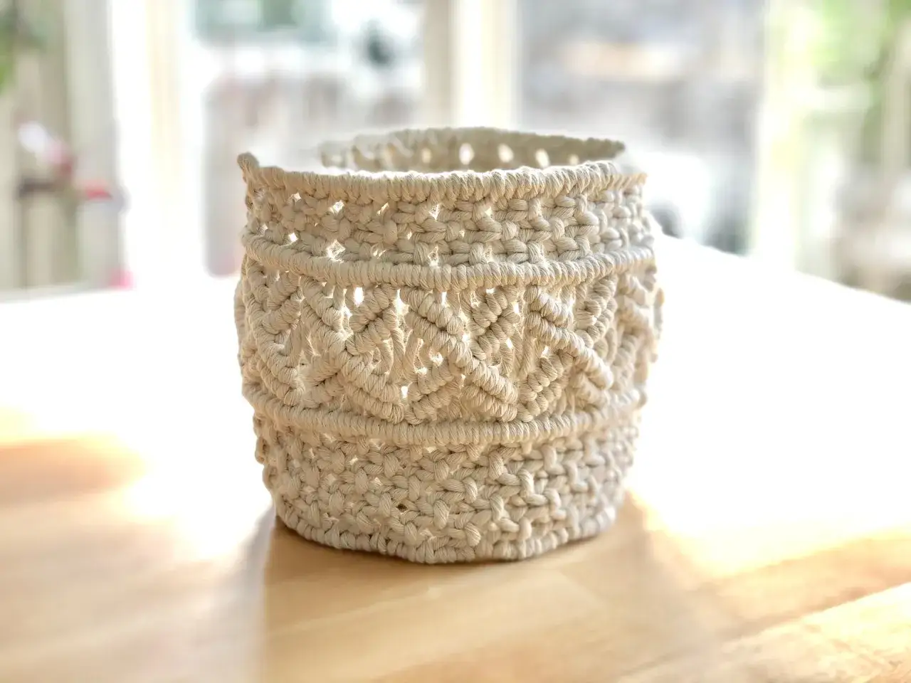 Ein handgefertigter Makramee-Korb aus cremefarbener Baumwolle, perfekt f&uuml;r boho pflanzen.