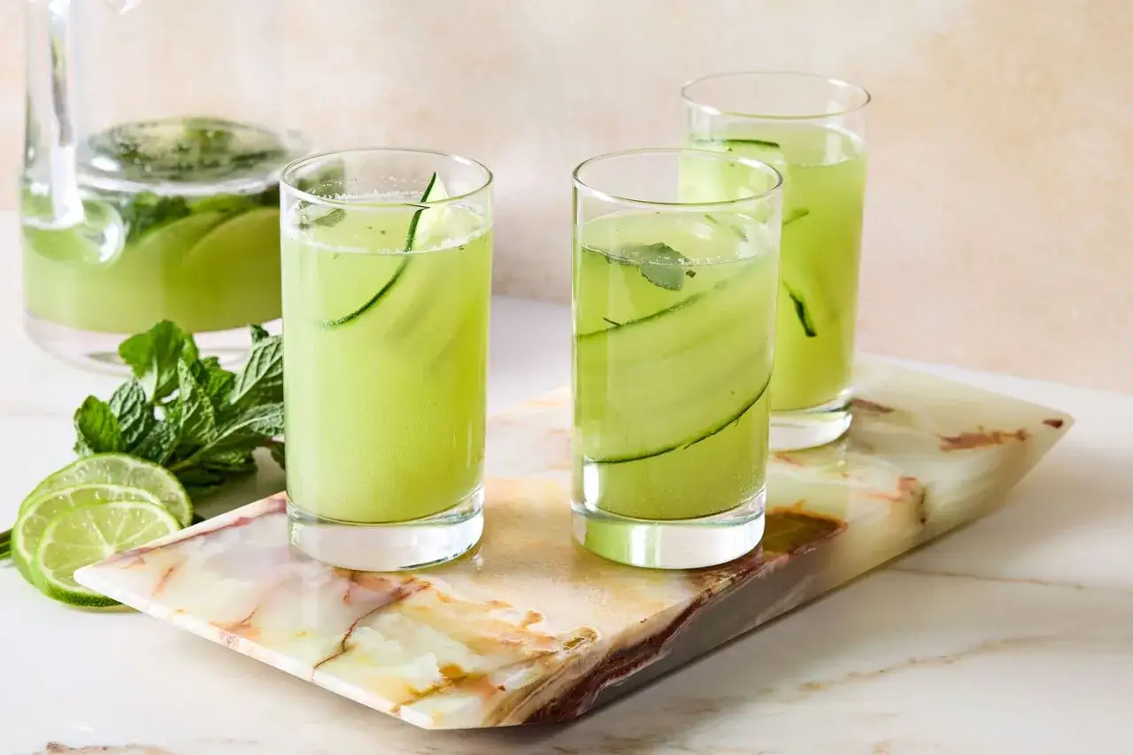 Orzeźwiający drink z ogórkiem, miętą i limonką, podany w szklankach na marmurowej desce.