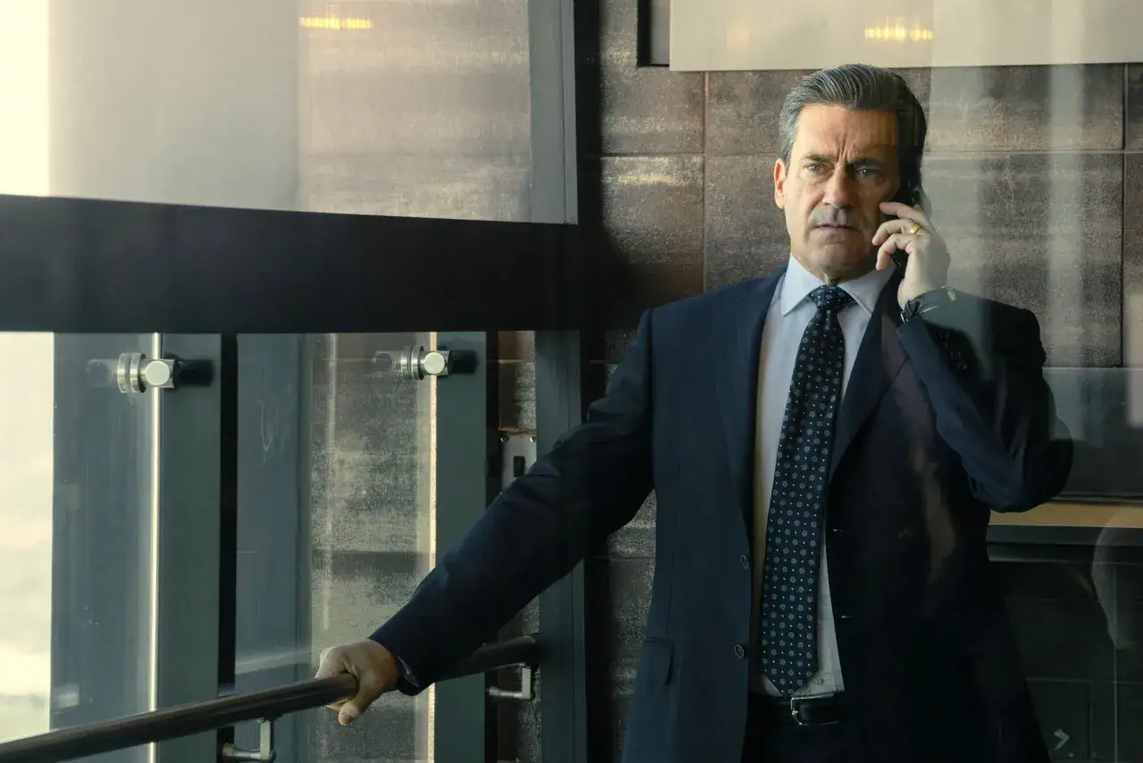 Jon Hamm w garniturze rozmawia przez telefon, przypominając postać z jego film&oacute;w i seriali.