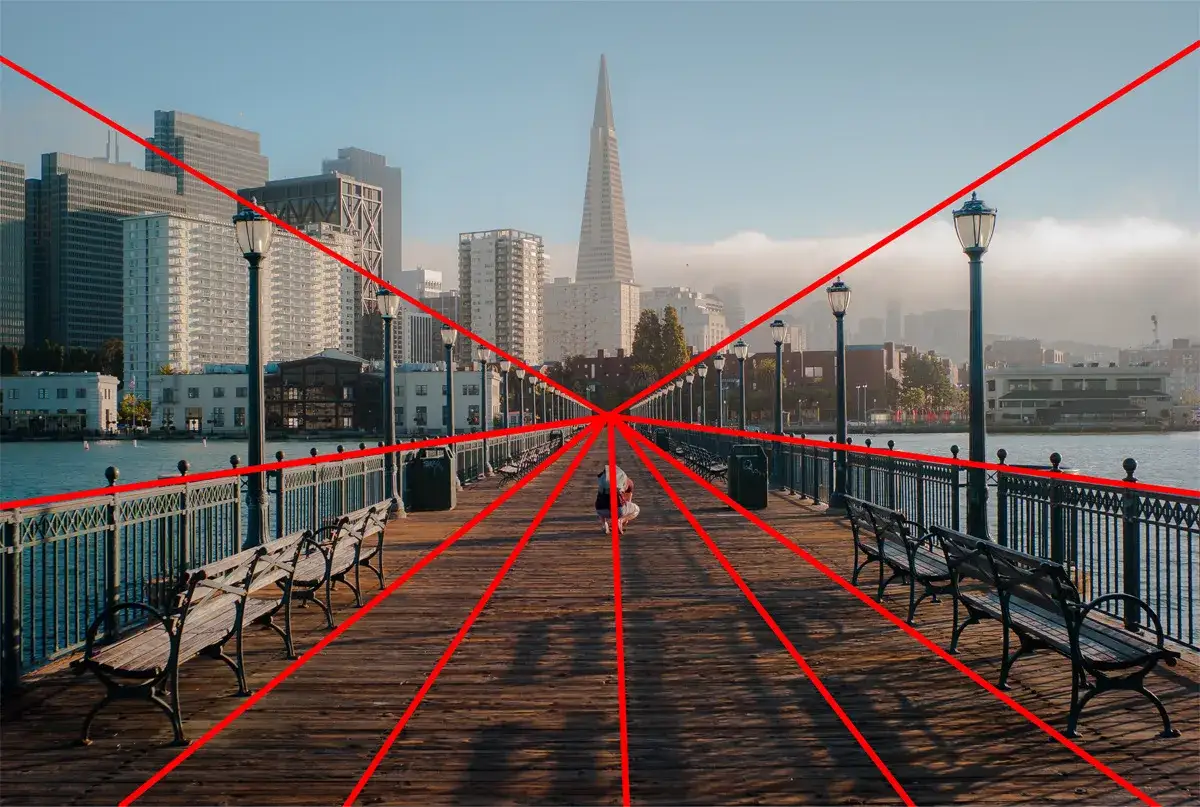 Un ponton avec des lignes rouges illustrant la règle de composition de la perspective. Au loin, la silhouette d'une ville.