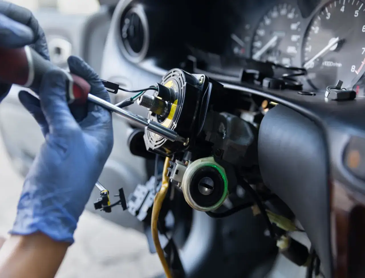 Mechanik w niebieskich rękawiczkach przykręca kolumnę kierownicy. Zastanawiasz się, ile kosztuje przełożenie kierownicy?
