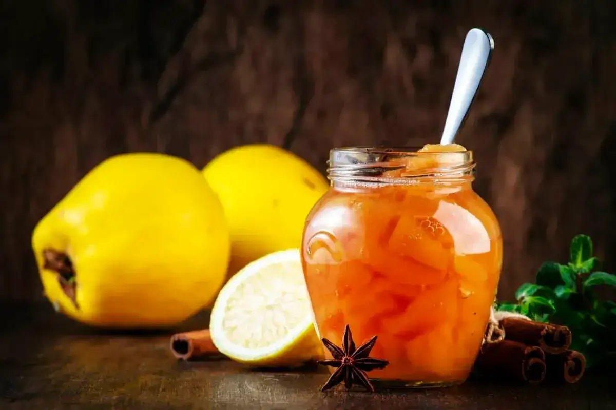 Confiture de coings aux épices, une touche de **gelatine pectine** pour une texture parfaite. Des coings jaunes, un citron, de la cannelle et de l'anis étoilé complètent la scène.