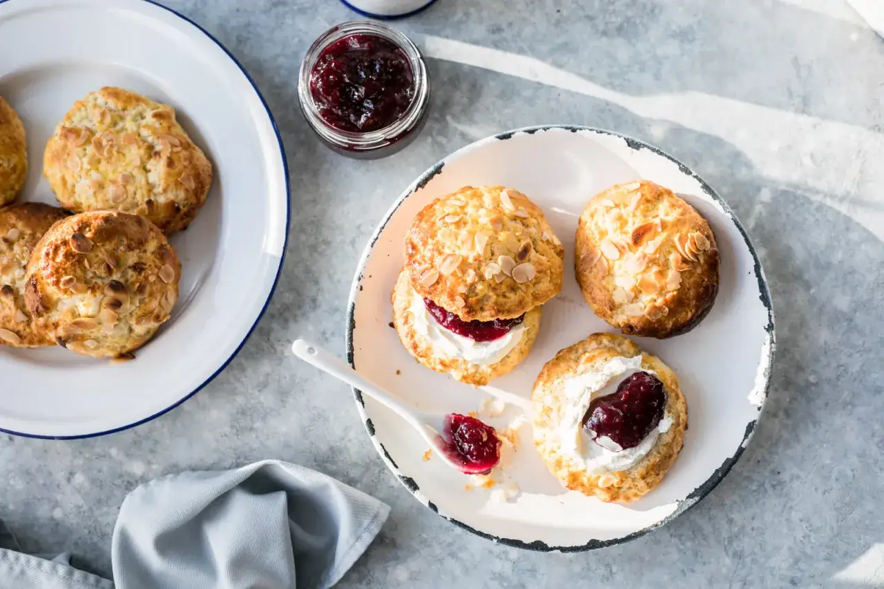 Luftiga scones med mandelflagor, serverade med vispad gr&auml;dde och sylt. En perfekt fika!