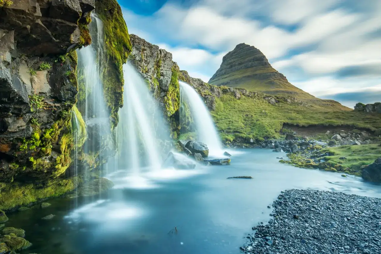 Majest&auml;tischer Wasserfall mit moosbewachsenen Felsen und dem ikonischen Berg Kirkjufell im Hintergrund. Ein perfektes Motiv f&uuml;r reiseziele august.