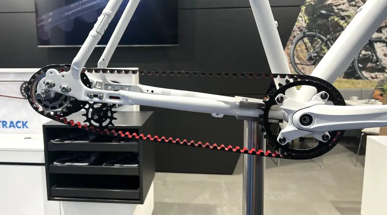 Close-up of a white belt drive mountain bike frame, showcasing the clean, chainless drivetrain with a red-edged belt.