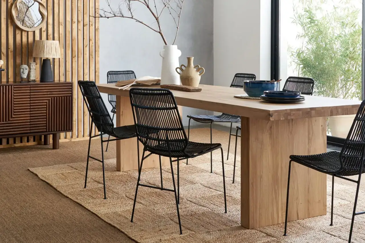 Salle &agrave; manger moderne avec table en bois clair et chaises noires. Le m&eacute;lange bois clair et bois fonc&eacute; du buffet cr&eacute;e un contraste chaleureux.