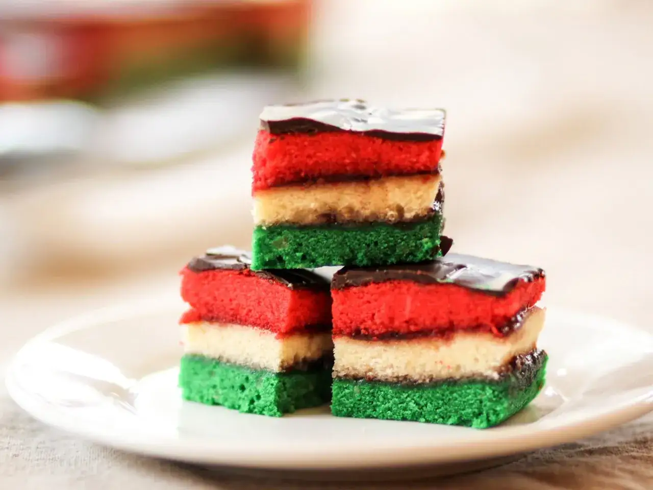 Trois parts de zuppa inglese empilées, aux couches rouge, blanche et verte, nappées de chocolat noir.