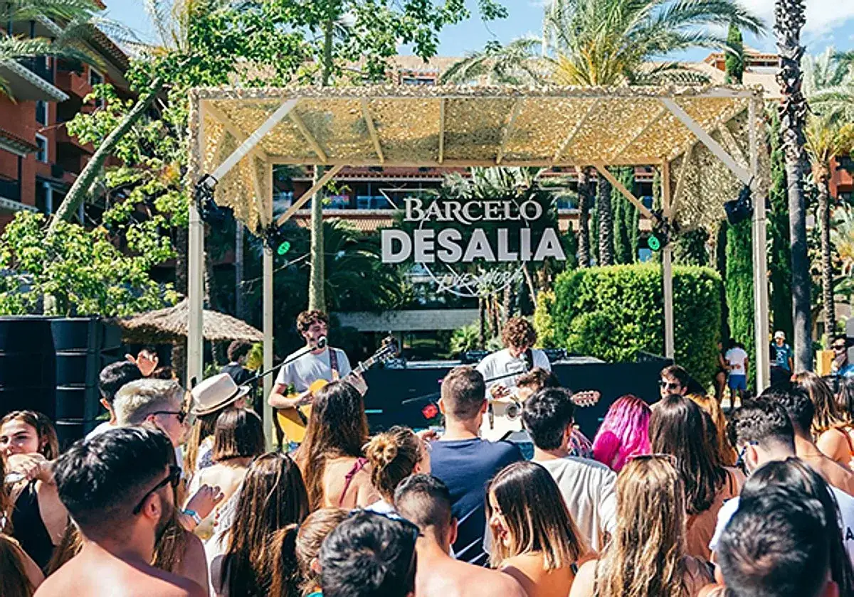 Un concierto en Desalia, un festival de música al aire libre con palmeras y un escenario.