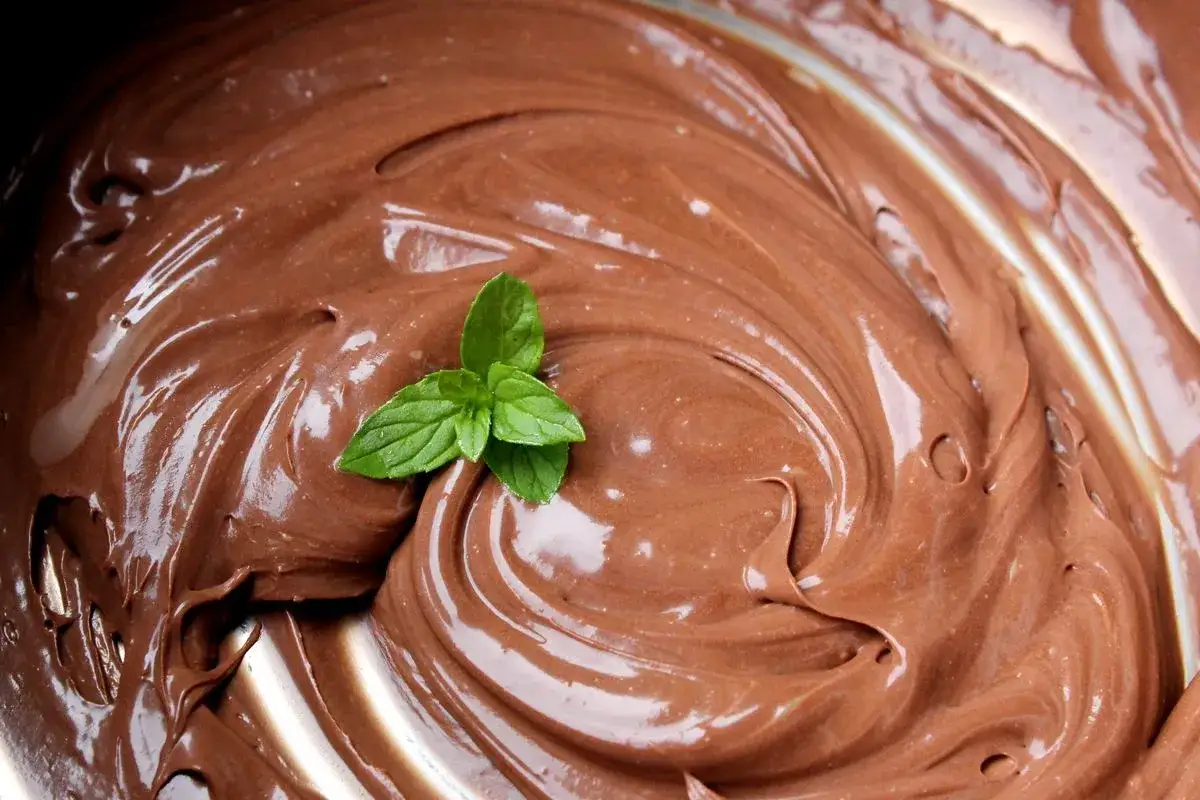 Una spirale di lucida ganache al cioccolato, decorata con una fogliolina di menta fresca.