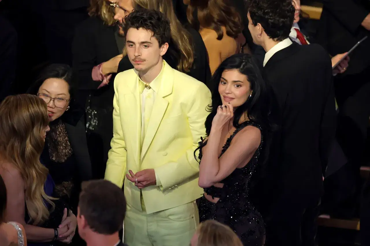 Kylie Jenner i Timothée Chalamet na wydarzeniu. Kylie w czarnej, błyszczącej sukience, Timothée w żółtym garniturze.