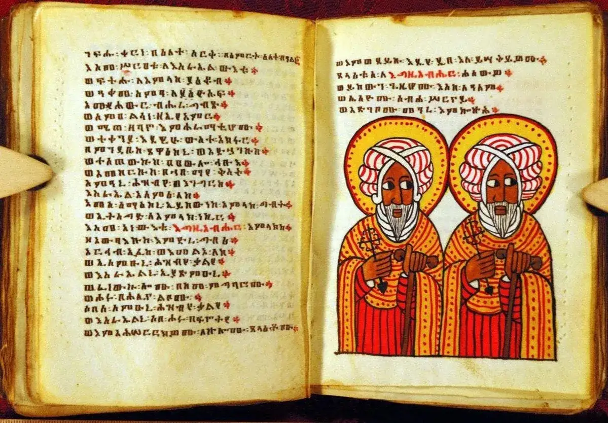 An open Ethiopian Bible with Ge'ez script and illustrations of two saints. This ancient text is a testament to Ethiopia's rich Christian heritage.
