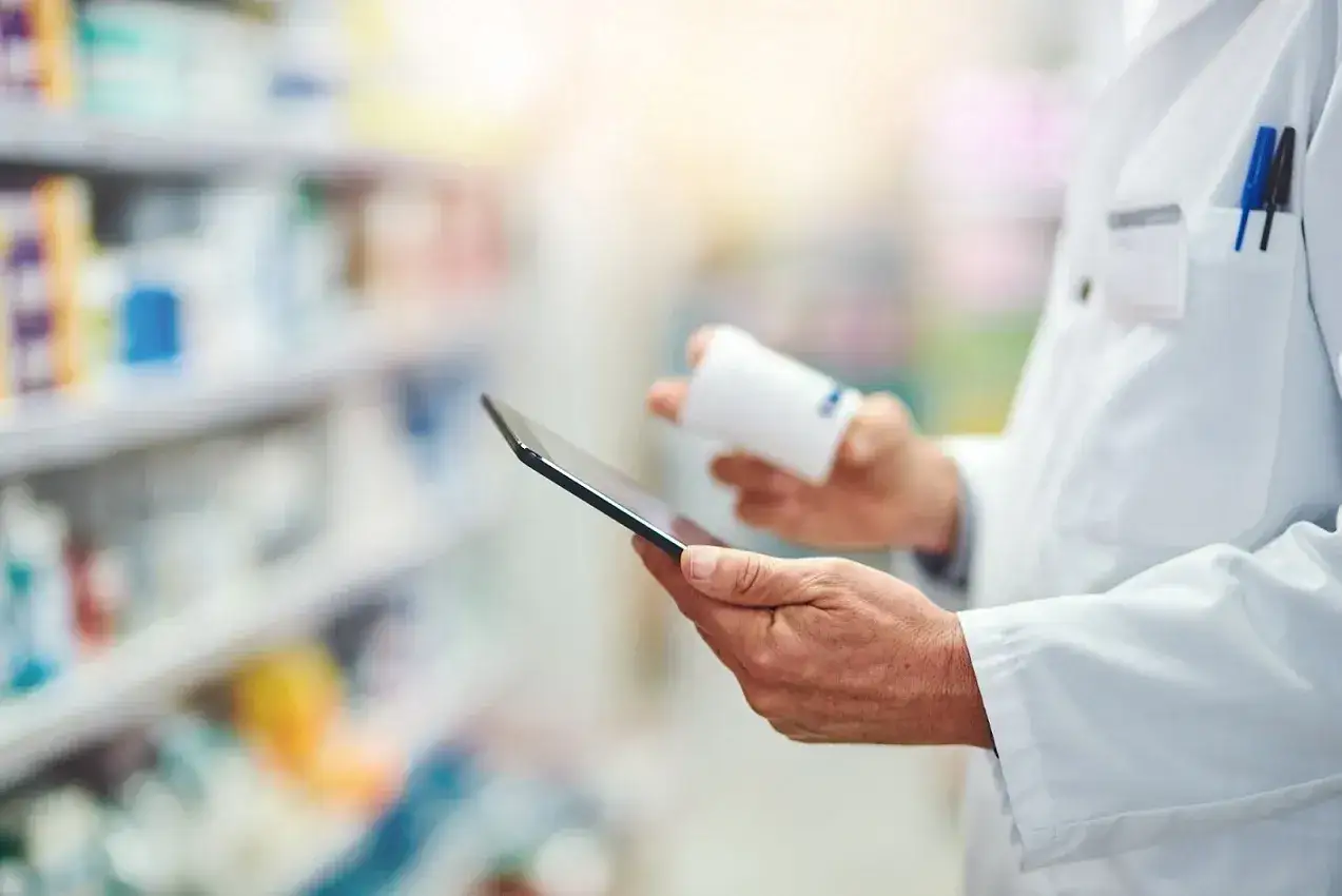 Farmaceuta sprawdza receptę na tablecie, przygotowując zwrot za leki dla senior&oacute;w.