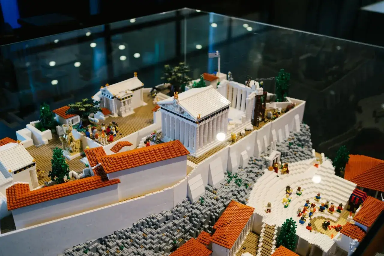 Maqueta de Atenas con niños jugando entre templos y edificios de ladrillos.